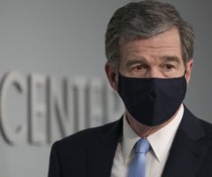 A man in a suit wearing a black mask.