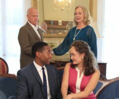 Two older people looking down on a younger couple sitting on a couch.